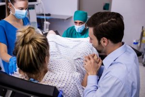 medical team examining pregnant woman during delivery while man holding her hand 300x200 - ¿Qué derechos tiene una mujer embarazada?