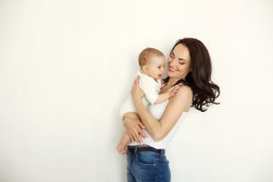 Young Happy Mother Smiling Holding Looking At Her Baby Daughter Over White Wall 1