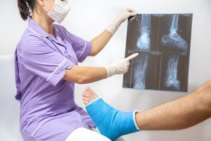 Bone Fracture Foot And Leg On Male Patient Being Examined By Woman Doctor In Hospital