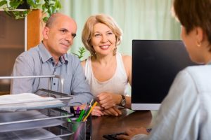 Aged Couple Of Pensioners Talking With Employee